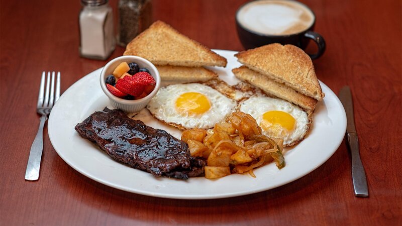 Steak, eggs and potatoes with a side of fruit and toast